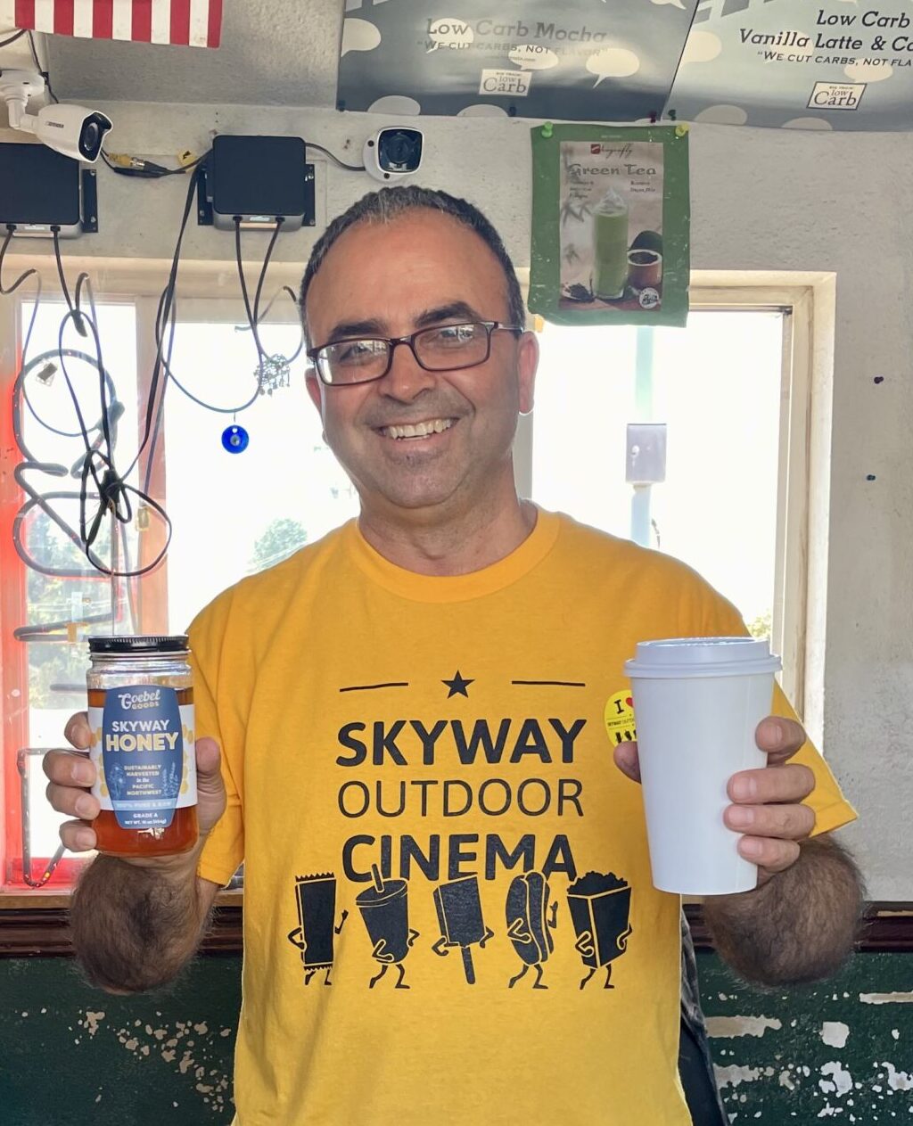 Nevzat Cankaya holding a jar of Skyway Honey and a cup of coffee.